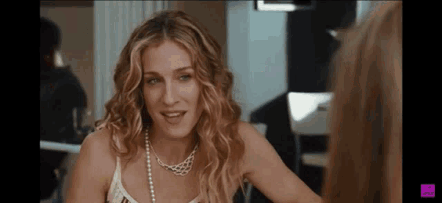 a woman wearing a pearl necklace is smiling