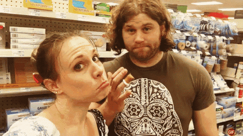 a man wearing a darth vader shirt stands next to a woman making a face