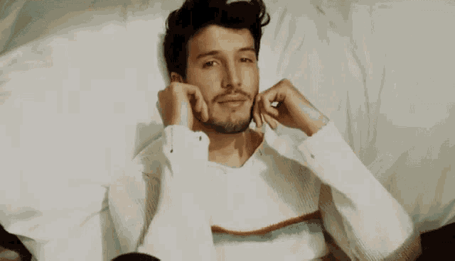 a man with a beard is smiling and wearing a white shirt