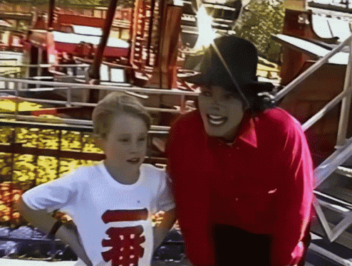 a man in a red shirt is standing next to a young boy in a white shirt with chinese characters on it .