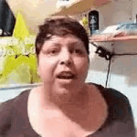 a woman is making a funny face while sitting in front of a wall .
