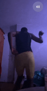 a man in a black tank top and yellow shorts is standing in front of a purple wall