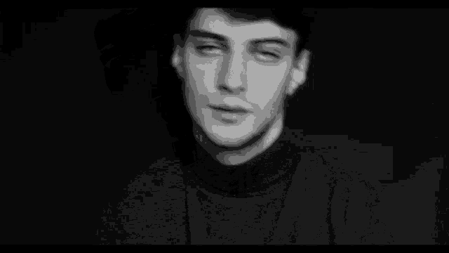 a black and white photo of a man in a turtleneck sweater .
