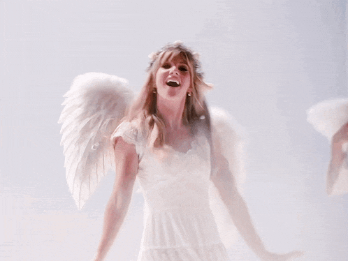 a woman in a white dress has angel wings on her arms