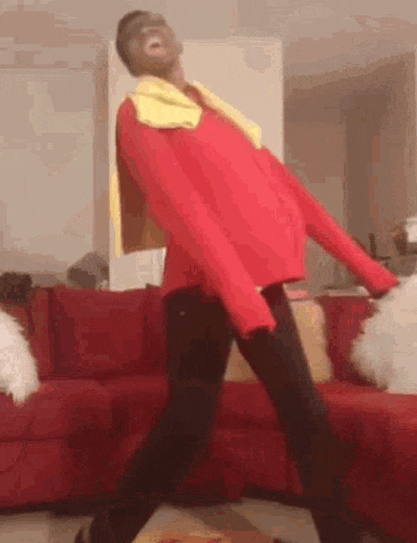 a person is standing in front of a red couch wearing a red jacket and a yellow scarf .