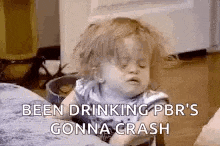 a little girl is sitting on a couch with her eyes closed and has been drinking .