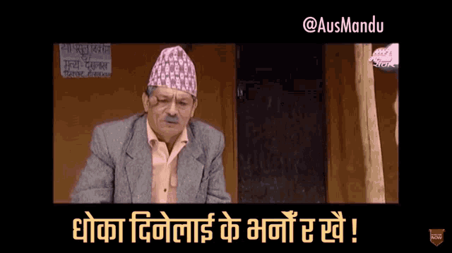 a man in a suit and a hat is sitting in front of a sign that says ' shree '