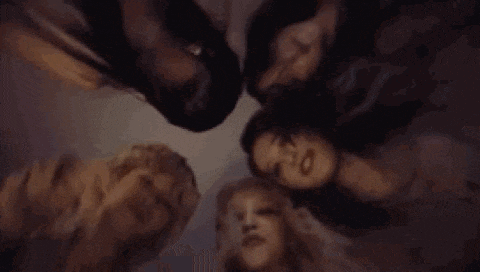 a group of women are laying in a circle with their heads on each other .