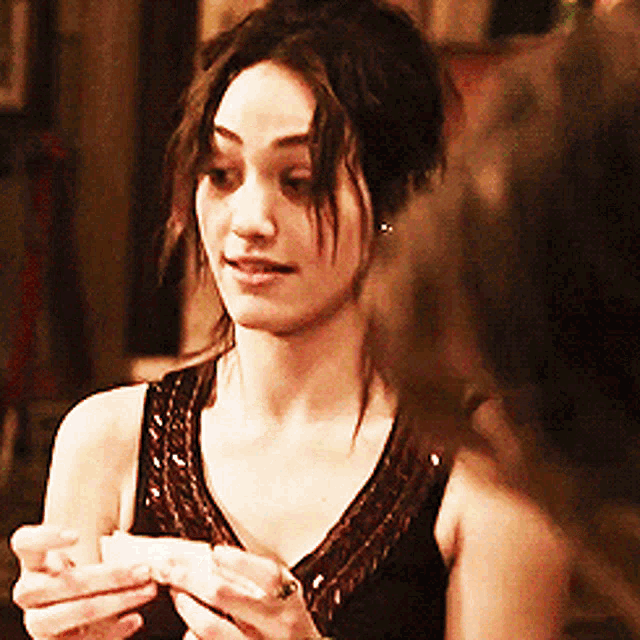 a woman in a black dress is holding a piece of paper