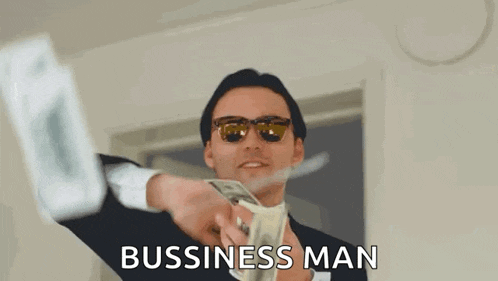 a man in a suit and sunglasses is holding a bunch of money in his hands .