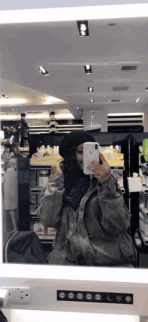 a woman taking a picture of herself in a store mirror