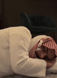 a man wearing a head scarf is laying on the floor with his head on a pillow