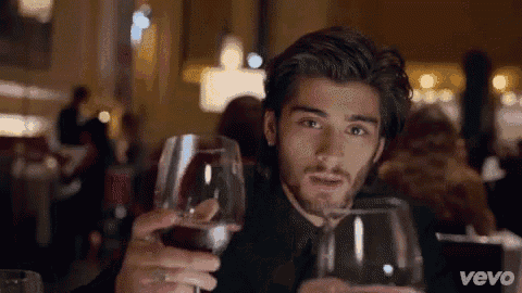a man in a suit is holding a glass of wine in a restaurant .
