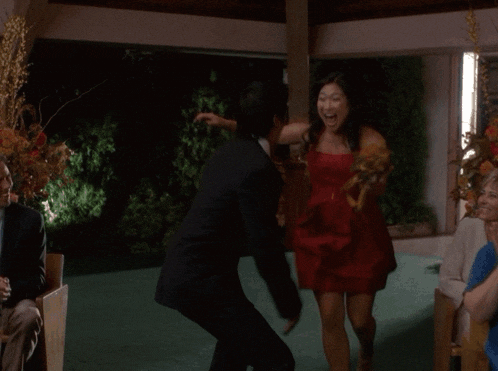 a man in a suit holds a woman in a red dress in his arms