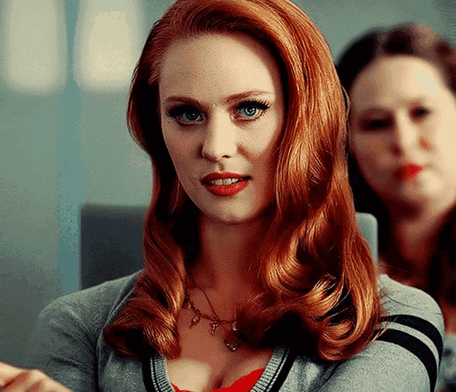a woman with red hair is wearing a necklace