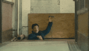 a man in a blue jacket is standing in a room with a sign on the wall that says ' ec '