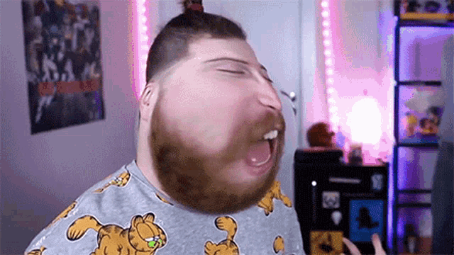 a man with a beard wearing a garfield sweater is making a funny face .