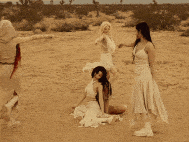 a woman in a white dress is laying on the ground in the desert