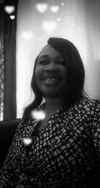 a woman is smiling in a black and white photo while sitting on a couch .