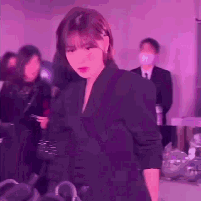 a woman in a black suit is standing in front of a group of people .