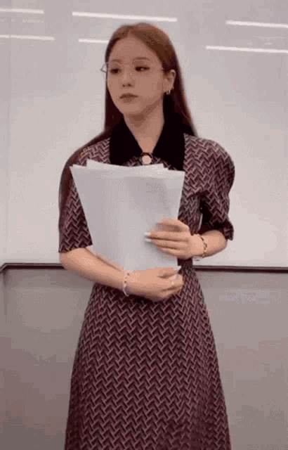a woman in a dress is holding a piece of paper in her hand .