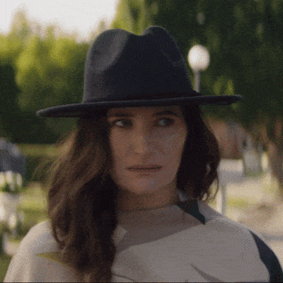 a woman wearing a hat and a scarf looks at the camera