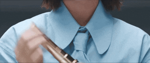 a woman wearing a blue shirt and tie is holding a flute