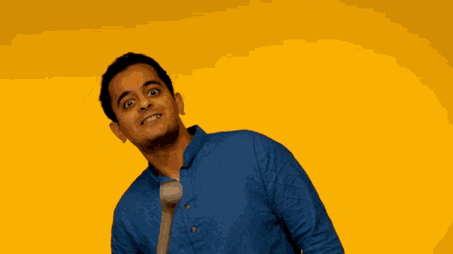 a man in a blue shirt is smiling while holding a wooden stick