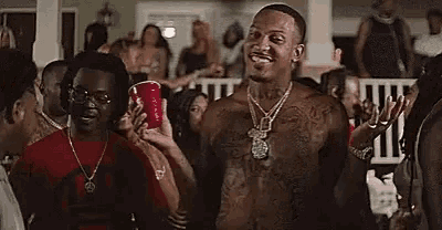 a shirtless man is holding a red cup in a crowd of people .