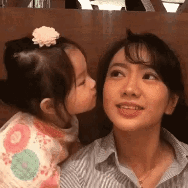 a little girl kissing a woman on the cheek .