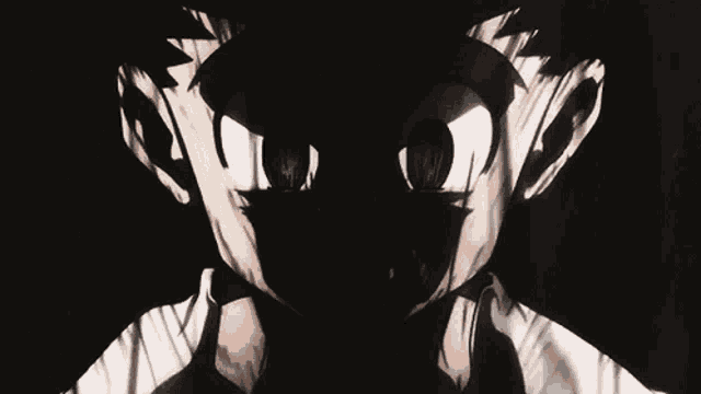 a close up of a person 's face in the dark with a shadow of a person behind them .