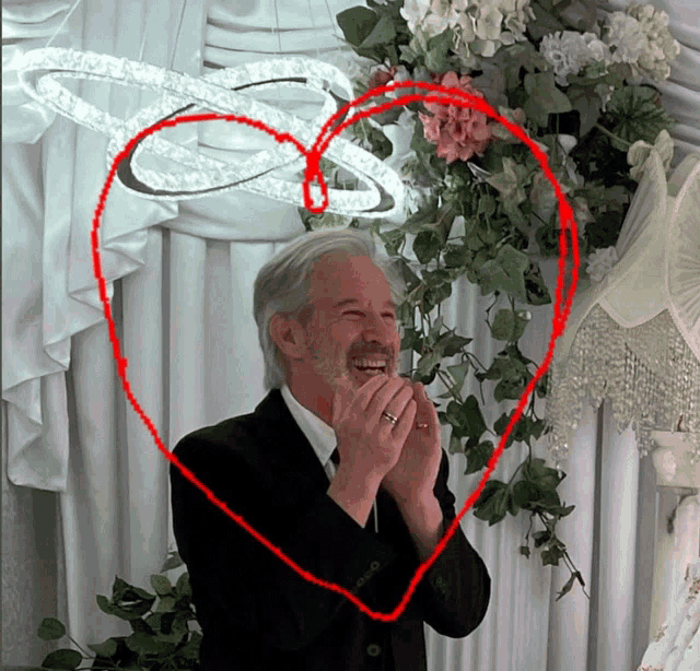 a man in a suit and tie is laughing in front of a heart