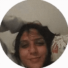 a close up of a woman 's face in a circle with a pillow in the background