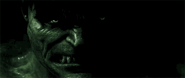 a close up of the face of the incredible hulk with green eyes and teeth .
