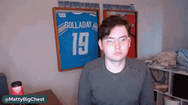 a man stands in front of a framed jersey that says golladay