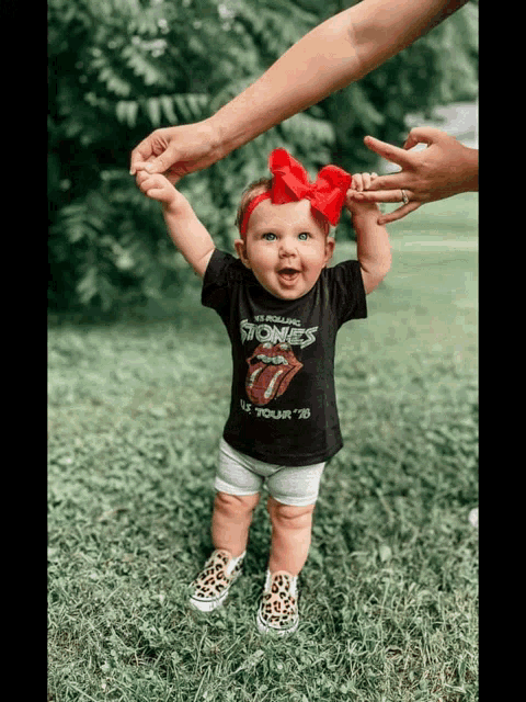 a baby wearing a rolling stones t-shirt is being held by a woman