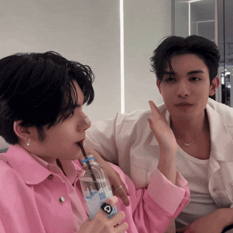 a man in a pink jacket is drinking from a bottle with a straw that has the letter c on it