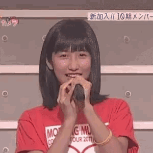a girl in a red shirt is holding a microphone in front of her face .