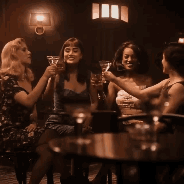 a group of women are toasting with martinis in a dark room