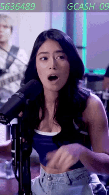 a woman singing into a microphone with the number 5636489 on the bottom right