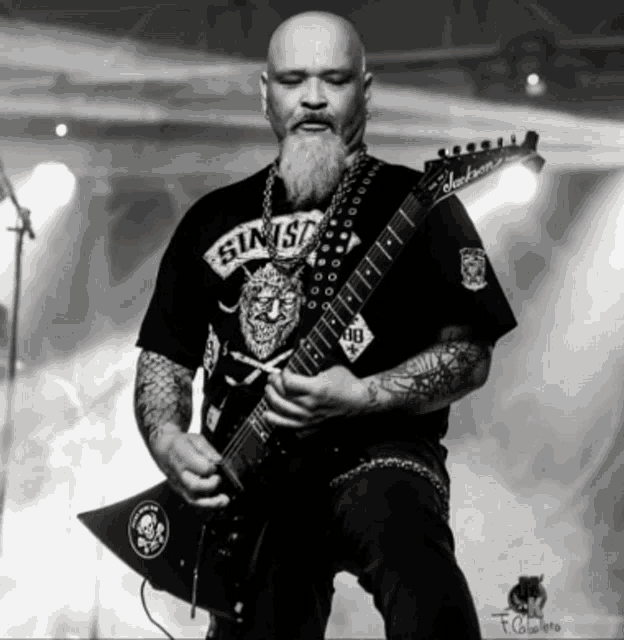 a man playing a guitar with a shirt that says sins on it