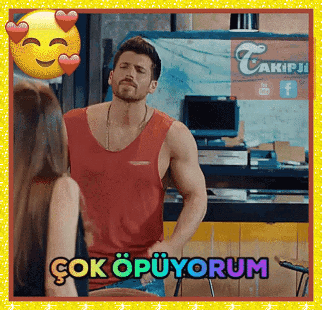 a man in a red tank top stands in front of a sign that says ' çok opuyorum ' on it