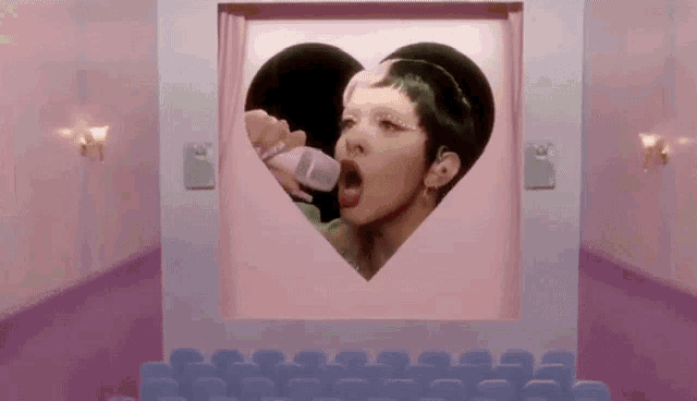 a woman is drinking from a baby bottle in a heart shaped window .