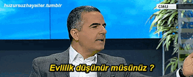 a man in a suit is speaking in a foreign language and says " evlilik düşünür musunuz "