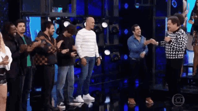 a group of people are standing next to each other on a stage and shaking hands .