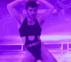 a man in a swimsuit is dancing on a stage in a purple light .
