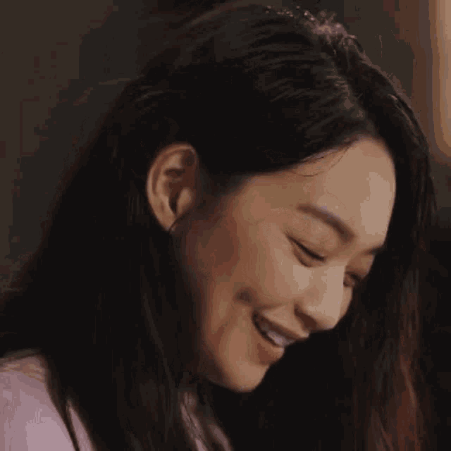 a close up of a woman 's face with long hair smiling .