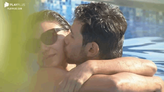 a man is kissing a woman on the forehead in a pool .