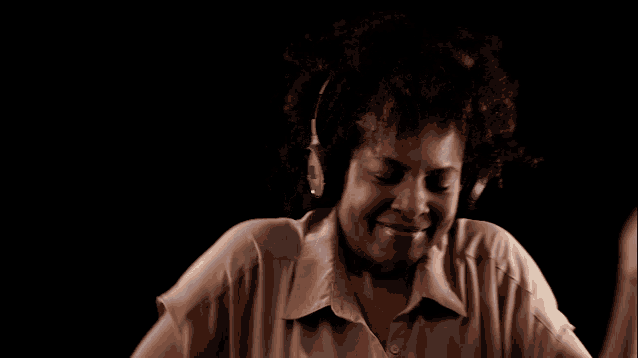 a woman wearing headphones is dancing with her arms in the air