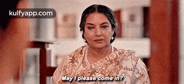 a woman in a saree is sitting in a room and talking to someone .